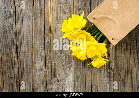 Yellow Daffodils in sacchetto di carta sul tavolo in legno Foto Stock