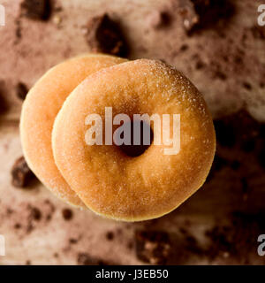 Alta angolazione di una pila di zucchero ciambelle vetrata su una tavola in legno rustico cosparso con piccoli pezzi di cioccolato Foto Stock