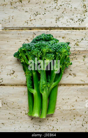 Alta angolazione di alcuni steli di broccolini su un bianco tavola in legno rustico Foto Stock