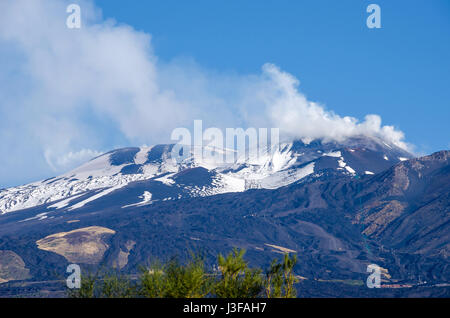 Il monte Etna, un attivi Stratovulcano, da sud con il picco di fumo nella parte superiore sinistra, fianchi innevati e linea della cabinovia in provincia di Catani Foto Stock