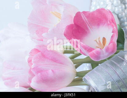 Rosa fresca tulipani sul cesto di vimini decorano la perla e il nastro. Primo piano e sfondo morbido Foto Stock
