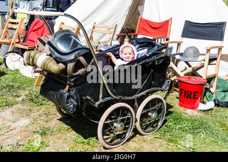 Saluto alla 40's rievocazione evento. Bambino nella PRAM con maschera a gas sospesi dal manubrio. La bambola guardando al visualizzatore. Foto Stock