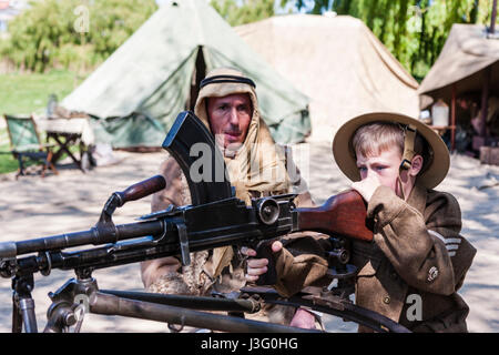 Saluto alla 40s rievocazione. Bambino, ragazzo biondo, 6-7 anni, nell'esercito britannico uniforme, essendo mostrata come fire Bren gun dal deserto soldato di ratto. Foto Stock