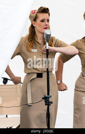 Saluto alla 40s rievocazione giorno. Il cantante da Knightingales, un trio di donne un gruppo di canto in WAAF uniformi, sul palco di eseguire la guerra mondiale due canzoni Foto Stock