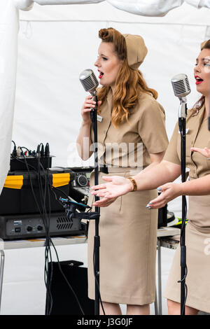 Saluto alla 40s rievocazione giorno. Il cantante da Knightingales, un trio di donne un gruppo di canto in WAAF uniformi, sul palco di eseguire la guerra mondiale due canzoni Foto Stock