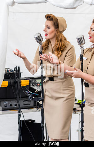 Saluto alla 40s rievocazione giorno. Il cantante da Knightingales, un trio di donne un gruppo di canto in WAAF uniformi, sul palco di eseguire la guerra mondiale due canzoni Foto Stock