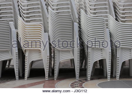 Sedie in plastica bianca impilati uno sull'altro prima di un evento Foto Stock