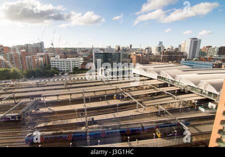 Leeds, Inghilterra - Giugno 28, 2015: Guardando attraverso treni di attesa presso le piattaforme di Leeds Stazione Ferroviaria per lo skyline del centro cittadino. Foto Stock