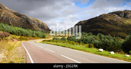 Una strada corre attraverso balze di montagna a Lochcarron nel West Highlands della Scozia. Foto Stock