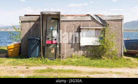 Un abbandonati nella casella Telefono e casolare accanto al molo del traghetto a Camusnagaul, di fronte a Fort William sul Loch Linnhe nel West Highlands della Scozia. Foto Stock