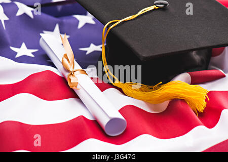 Vista ravvicinata di graduazione mortarboard e diploma a noi bandiera, il concetto di istruzione Foto Stock