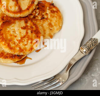 In casa cottage cheese pancake con caramello (miele) su una piastra bianca. Foto Stock