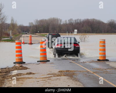Veicoli corssing una strada allagata causato dalla molla pesante pioggia in Quebec, Canada Foto Stock