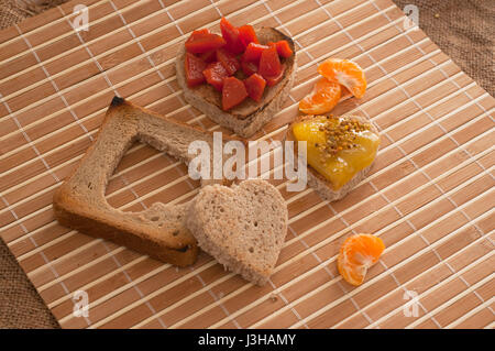 Il giorno di San Valentino la colazione, tostapane forma di cuore con marmellata sullo sfondo di legno Foto Stock