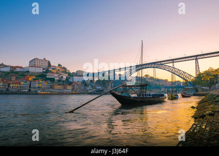 Città di Douro Porto, vista di una tradizionale barca rabelo sul fiume Douro con lo skyline di Porto all'alba sullo sfondo, Portogallo, Europa. Foto Stock