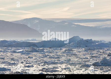 Un alloggiamento riempito di iceberg e bergy bit con montagne e ghiacciai visibili a distanza Foto Stock