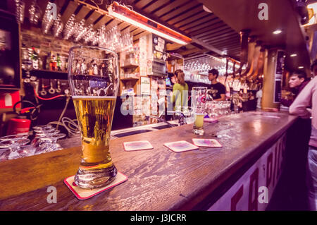 Bruxelles, Belgio - 11 August, 2015: Bicchiere di birra seduti sul bancone bar all'interno di delirio Bar, selezione di altre bevande in background. Foto Stock