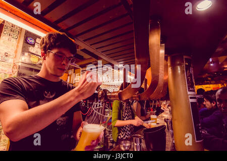 Bruxelles, Belgio - 11 August, 2015: barista al delirio Bar toccando la birra in bicchiere alto con diversi altri rubinetti accanto ad essa. Foto Stock