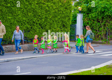 OSLO, Norvegia - 8 July, 2015: gruppo di asilo nido i bambini a camminare su una linea di indossare giubbotti di riflettere , a capo per Vigelandsparken. Foto Stock
