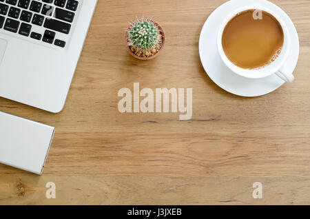 Scrivania in legno tavolo con computer laptop, disco rigido esterno, cactus e tazza di caffè. Vista da sopra con copia spazio, laici piana. Foto Stock