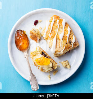 Cornetto con marmellata e burro sulla piastra. Sfondo blu. Vista dall'alto. Copia dello spazio. Foto Stock