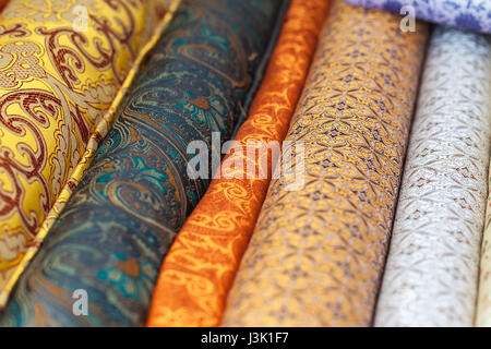 Rotoli di tessuti e prodotti tessili in un negozio della fabbrica. Multi colori e motivi diversi sul mercato Foto Stock