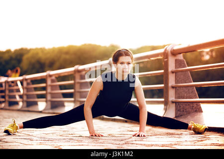 Yong femminile con bella figura facendo stretching prima di esercizio ha iniziato la sua esecuzione Foto Stock