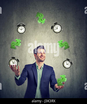 Il tempo è denaro concetto. Felice giovane impreditore juggling segni di dollaro e sveglia Foto Stock