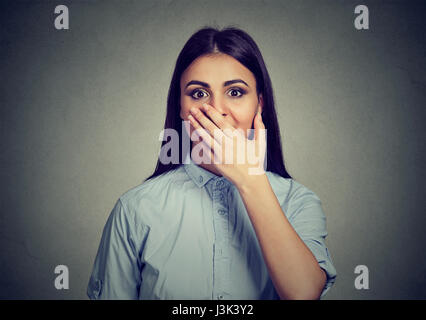 Donna che guarda sorpreso in piena incredulità mano sulla bocca spalancata isolato muro grigio Sfondo. Foto Stock