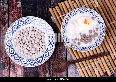 Thai dessert ,viola gli gnocchi di patate con uovo in camicia e rullo di noce di cocco in dolci crema di noce di cocco servita nel modello tailandese vaschetta . Chiamata Bua Loi Khai Waan in Foto Stock