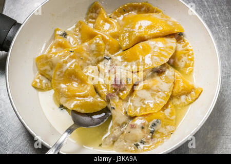 Mezza arrotondata. ravioli fatti in casa tipica pasta fresca in crema al formaggio con pancetta e rosmarino Foto Stock