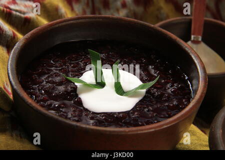 Tradizionale Dessert Giavanese Porridge di nero riso glutinoso sulle stoviglie di terracotta Foto Stock