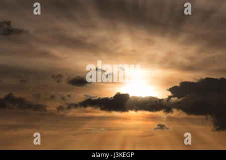 Sole che tramonta dietro belle nuvole con raggi di Dio Foto Stock