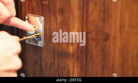 Mano d'uomo apre una serratura con una chiave nella porta. Foto Stock