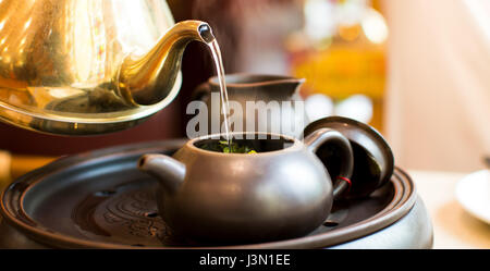 Acqua calda versando in teiera ceramica per la realizzazione di un set per la preparazione di tè Foto Stock