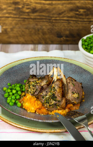 Il rosmarino costolette di agnello a cena con la carota e pastinaca mescolanza e piselli verdi Foto Stock