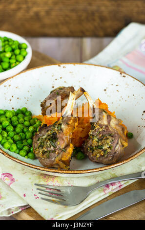 Il rosmarino costolette di agnello a cena con la carota e pastinaca mescolanza e piselli verdi Foto Stock