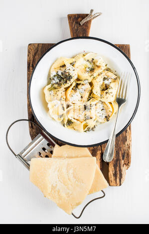 Italian tortellini burro e salvia con carne affumicata, burro e salvia su rustiche in legno su scheda dipinte di bianco sullo sfondo Foto Stock