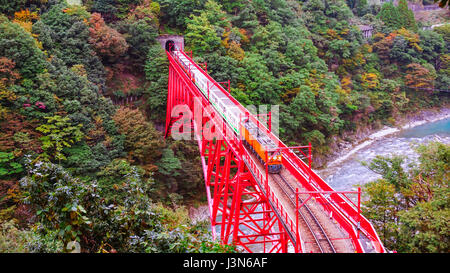 Treno su Shin Yamabiko ponte rosso di attraversare il fiume a stazione Unazuki in gola Kurobe Foto Stock