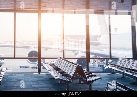 Aeroporto di vuoto boarding gate lounge con file di sedili e windows con la vista di un velivolo di grandi dimensioni pronto a volare Foto Stock