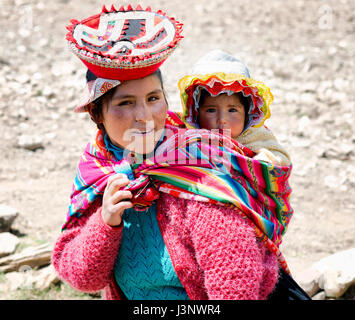 Close up ritratto di un sorridente Quechua donna vestita in colorate a mano tradizionale vestito e portando il suo bambino in una fionda. Ottobre 21, 2012 - Pat Foto Stock