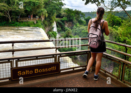 Giovane turista femminile guardando a Iguazu Falls (aka Iguassu Falls o Cataratas del Iguazú), Provincia Misiones, Argentina Foto Stock