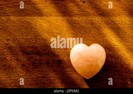 Quarzo rosa a forma di cuore laici piatta sul legno naturale. Foto Stock