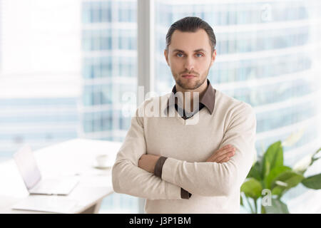 Successo serio giovane imprenditore in piedi in Office cerca Foto Stock