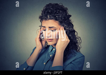 Triste closeup donna giovane con preoccupato ha sottolineato faccia avente espressione cefalea isolata sul muro grigio Sfondo. Le emozioni umane, salute mentale concetto Foto Stock