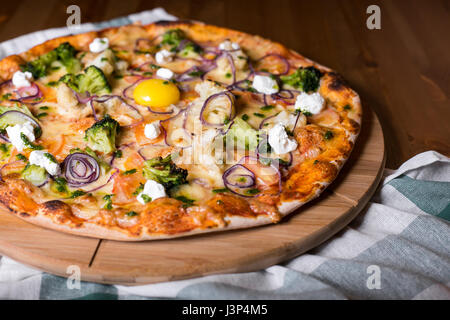 Freschi e deliziosi in casa la pizza con le cipolle, verdure e formaggio su di un tavolo di legno. Copia spazio. close-up Foto Stock