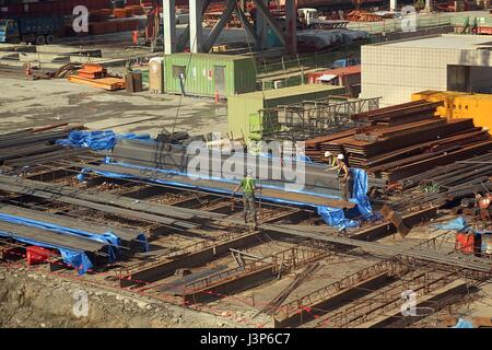 KAOHSIUNG, Taiwan - 31 Maggio 2014: i lavoratori spostare le travi in acciaio a un grande sito di costruzione presso la principale stazione ferroviaria di Kaohsiung. Foto Stock