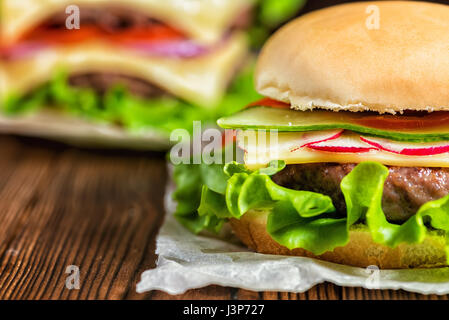 Close up di prodotti freschi fatti in casa con hamburger di manzo, cetriolo, Rafano, lattuga, formaggio e spezie in legno tavolo rustico Foto Stock