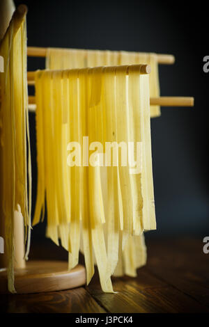 Pasta fatta in casa sono essiccati su un supporto in legno Foto Stock