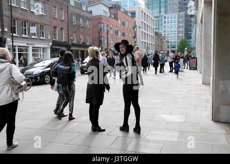 Attraente giovane donna vestita di nero hat sorridente in piedi con un amico su Brushfield Street vicino a Spitalfields Market in East London E1 KATHY DEWITT Foto Stock